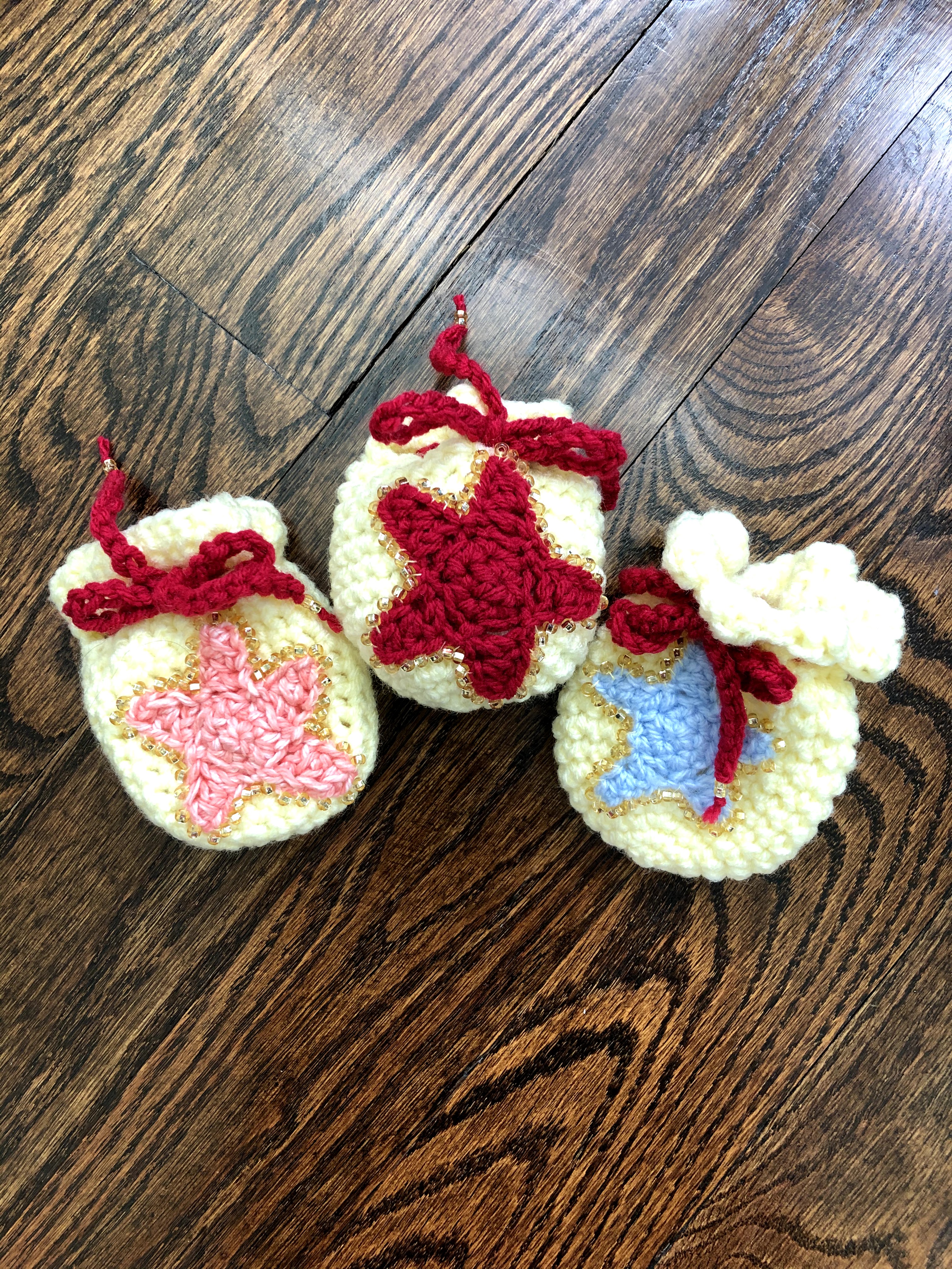 Inspired by a Reddit post and my friends' love for Animal Crossing, three Bell Bags customized with their favorite colors (orange, red, and blue stars on yellow pouches with red drawstrings).